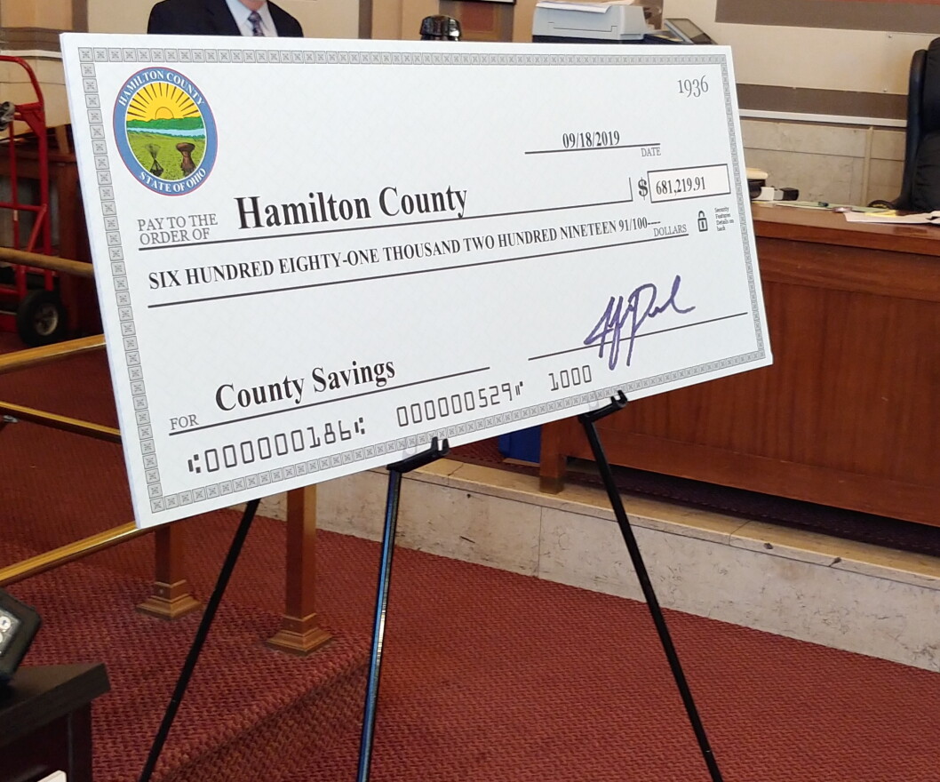 A giant ceremonial check represents the recovered money.